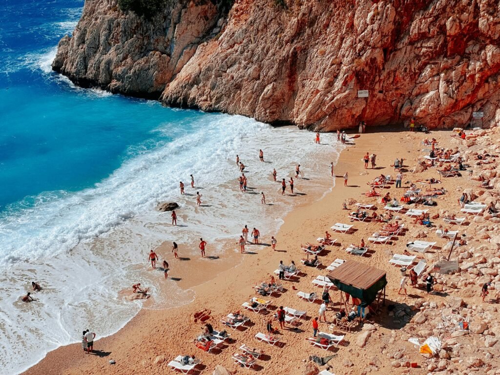 Aerial shot of people enjoying a sunny day on a Mediterranean beach with clear blue waters.